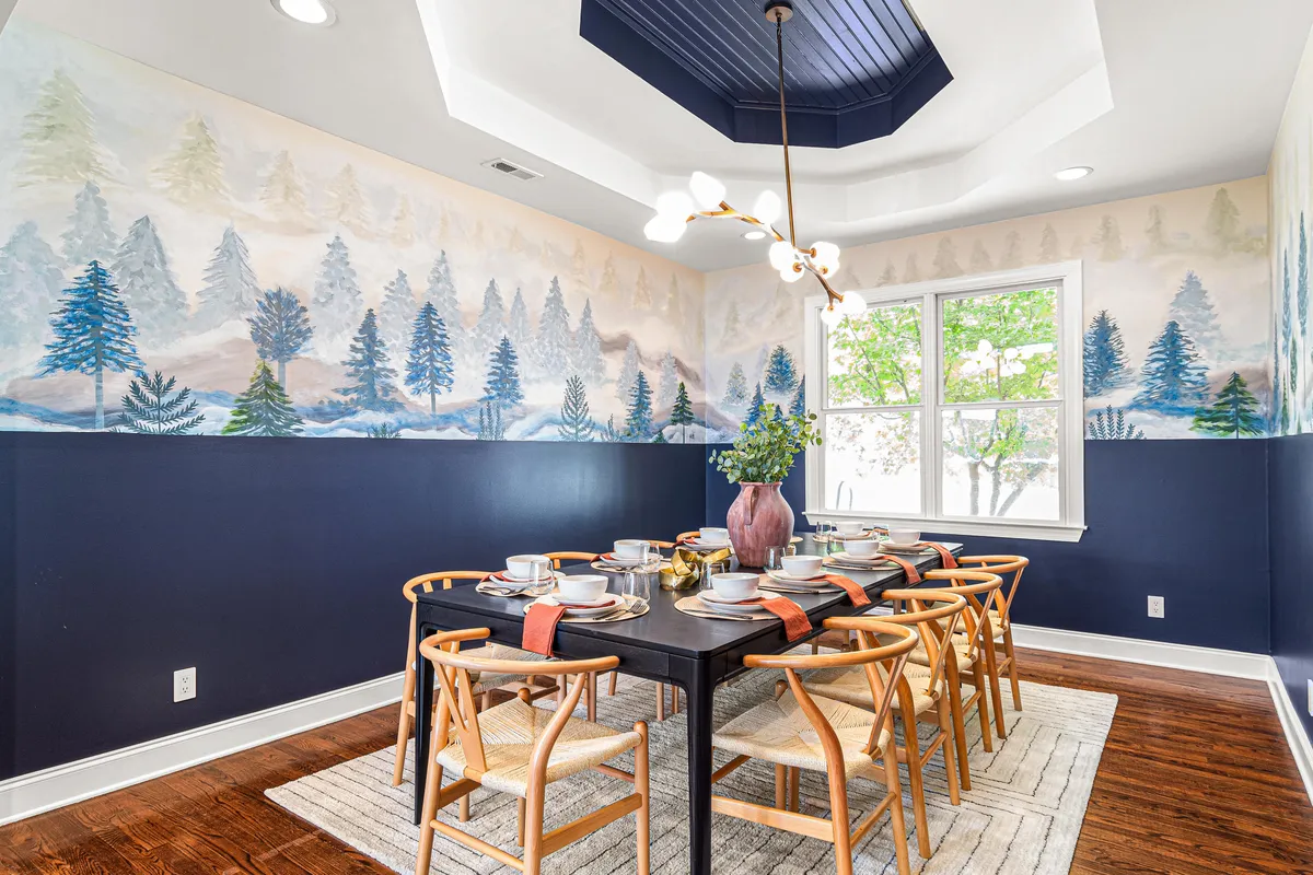 A beautifully set dining table stands as the focal point in a warm, welcoming dining area. A vibrant wall mural and striking light fixture enhance the ambiance, making it ideal for festive family feasts and milestone celebrations.