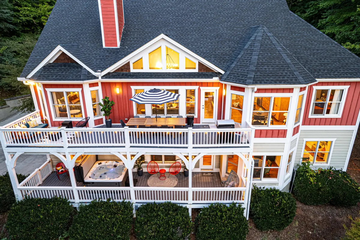 A vibrant shot of the home's colorful exterior, inviting outdoor seating area, and a bubbling hot tub on the patio. Surrounded by natural greenery, the image suggests a welcoming, fun gathering space after a day of adventure.