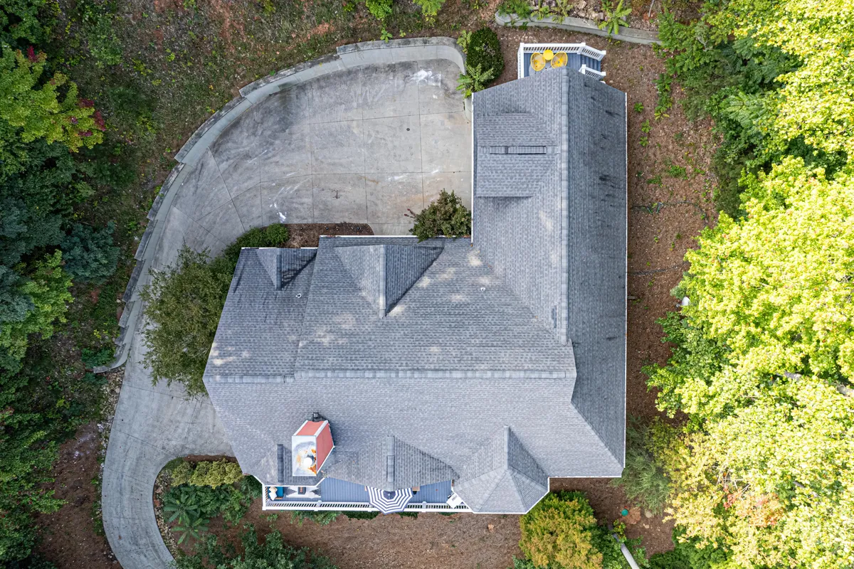 A tranquil exterior view of the Swannanoa Sanctuary, framed by lush trees and a circular driveway. The house is nestled in nature, offering a sense of privacy and serenity that sets the stage for a luxury retreat close to Asheville.