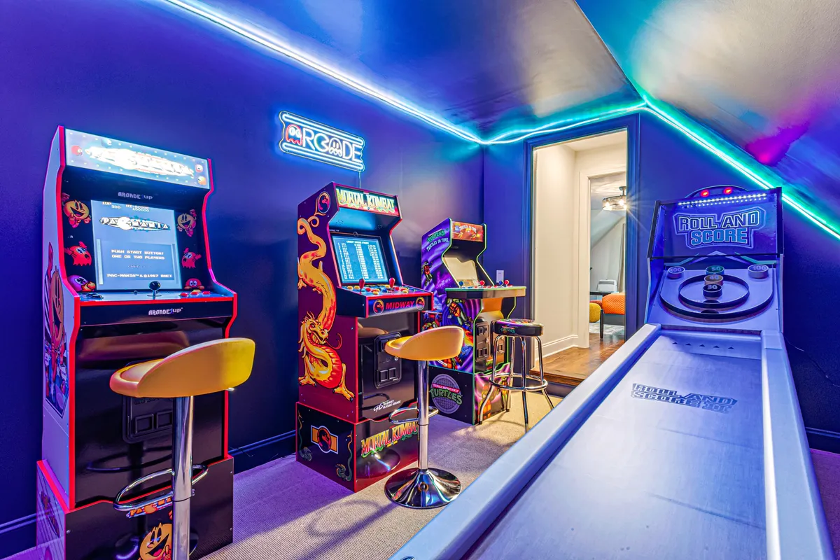 A vibrant arcade room featuring multiple vintage arcade machines, glowing neon lighting, and bar stools for socializing. The energetic, nostalgic vibe calls out for friendly competition and fun for all ages.